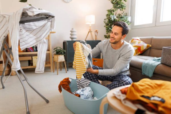Young handsome man with laundry at his living room